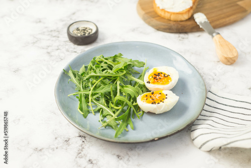 boiled eggs with arugula on a gray plate on gray background.
