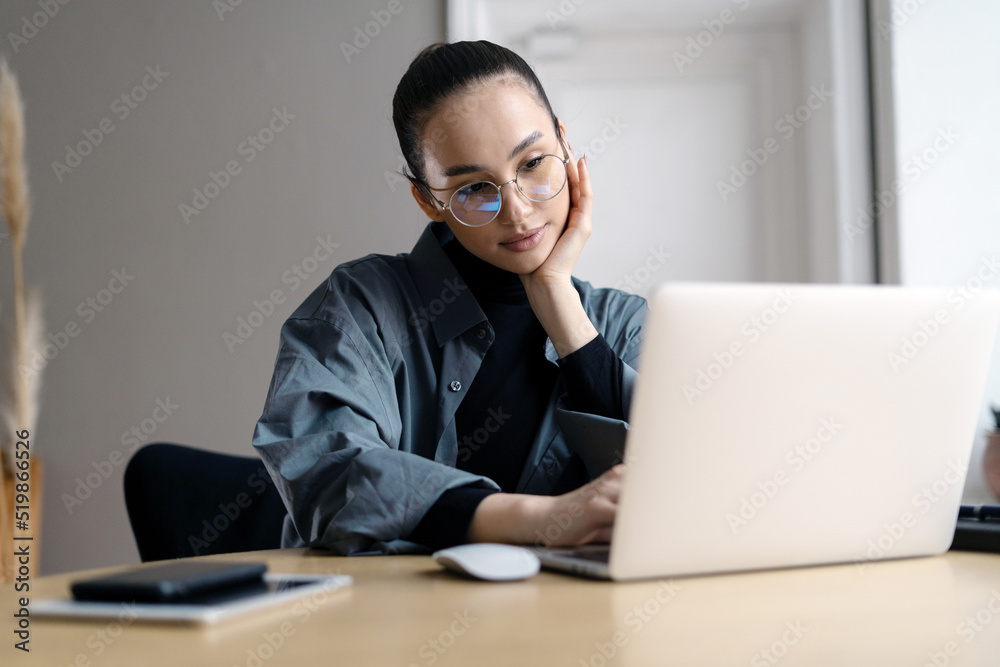 Stylish young woman freelancer working online writes a message using a laptop, a workplace in the office Stylish young woman freelancer working online writes a message using a laptop, a workplace in the office