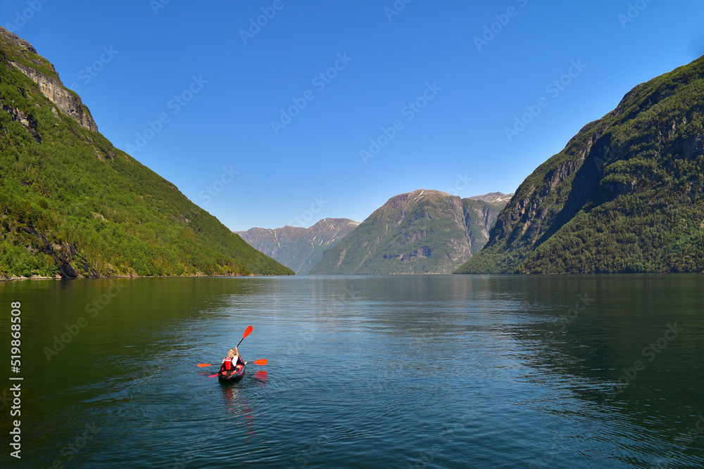 Couple kayaking across fjord in Geiranger region, Norway