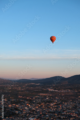 Vertical photo of hot air ballon flying over the city of Teotihuacan in Mexico