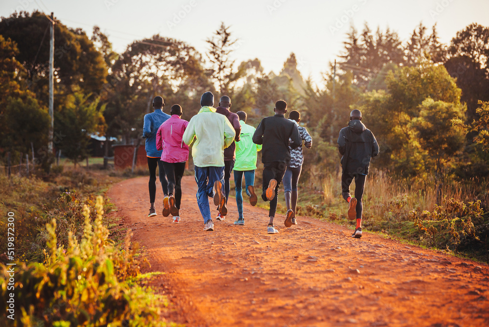 Fototapeta premium Morning running training in Kenya. A group of endurance runners run on red soil at sunrise. Morning running motivation for training.