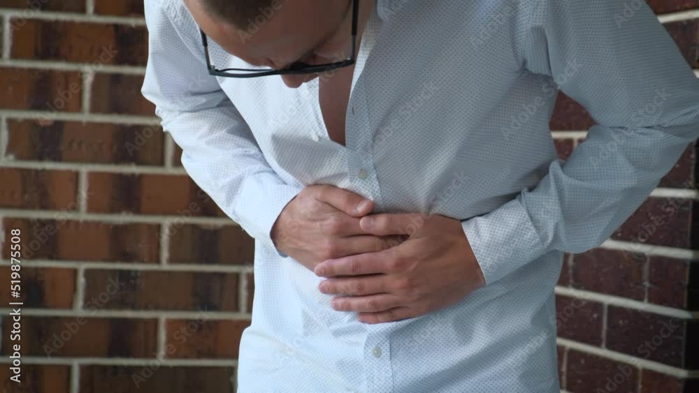 A man clutching his stomach with his hands feeling pain, close-up A man clutching his stomach with his hands feeling pain, close-up