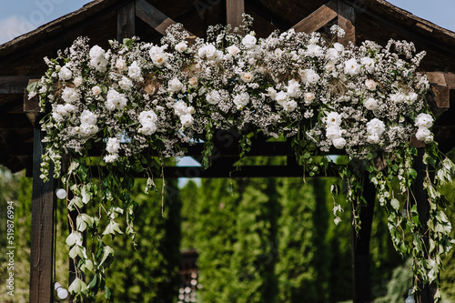 Beautiful white flowers  roses  wild flowers close-up on a wedding arch  wooden house. Photography of nature.