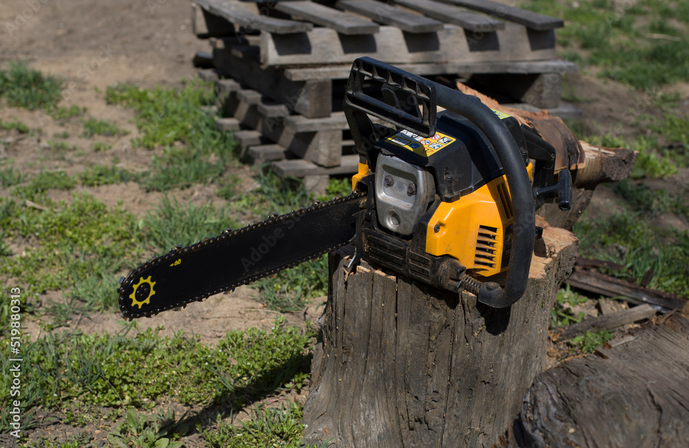 yellow automatic chainsaw on the street, on a wooden stump
