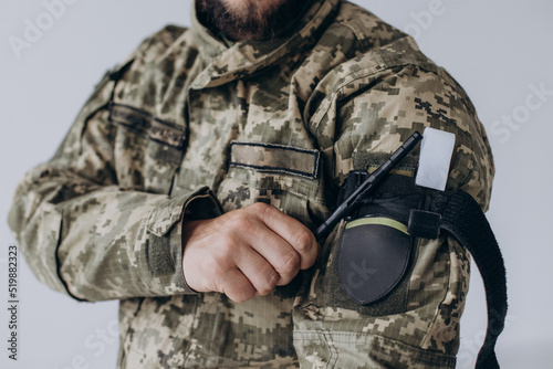 A military man demonstrates a combat medical tourniquet to stop blood during first aid. Instructions for combat tactical equipment.