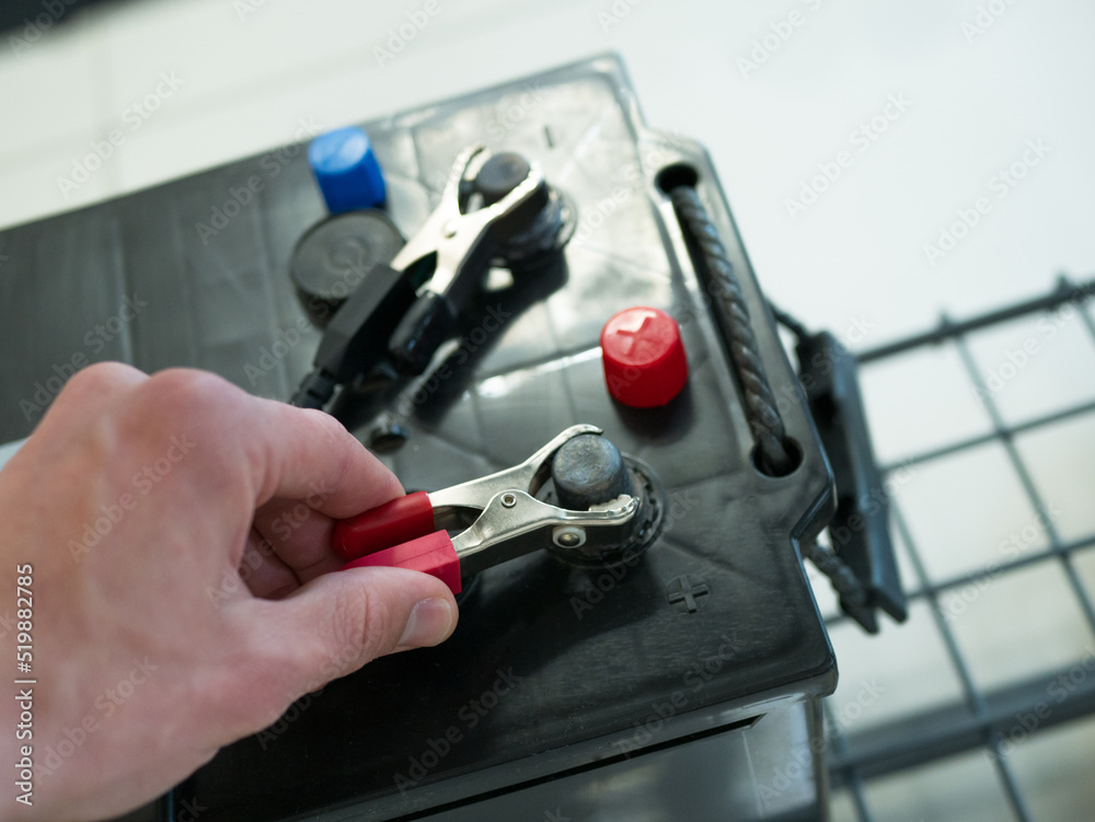 Fototapeta premium Checking car battery on battery terminals. Man test voltage