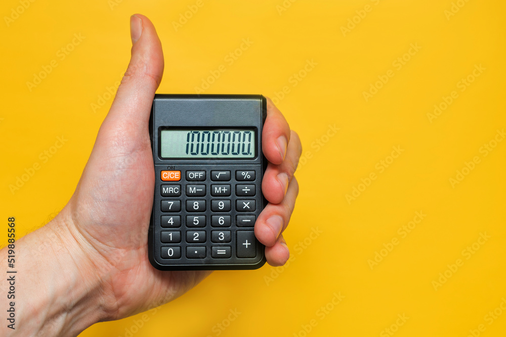 A man holds a calculator in his hand on a yellow background. The concept of high performance, price, payment A man holds a calculator in his hand on a yellow background. The concept of high performance, price, payment