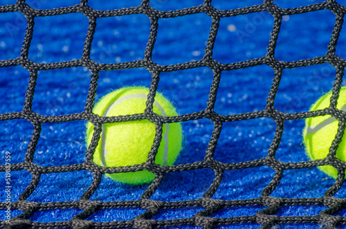A ball on a paddle court, behind the net. Racket sports