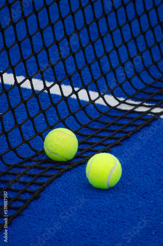 Blue paddle tennis court, two balls nearby the net © Vic