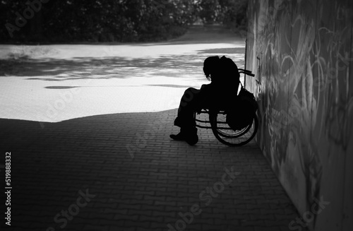 Tablou pe pânză Sad person sitting on a wheelchair on a dark street