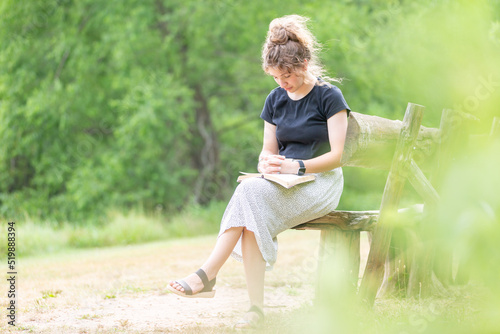 Young woman sitting on a bench reading the Bible