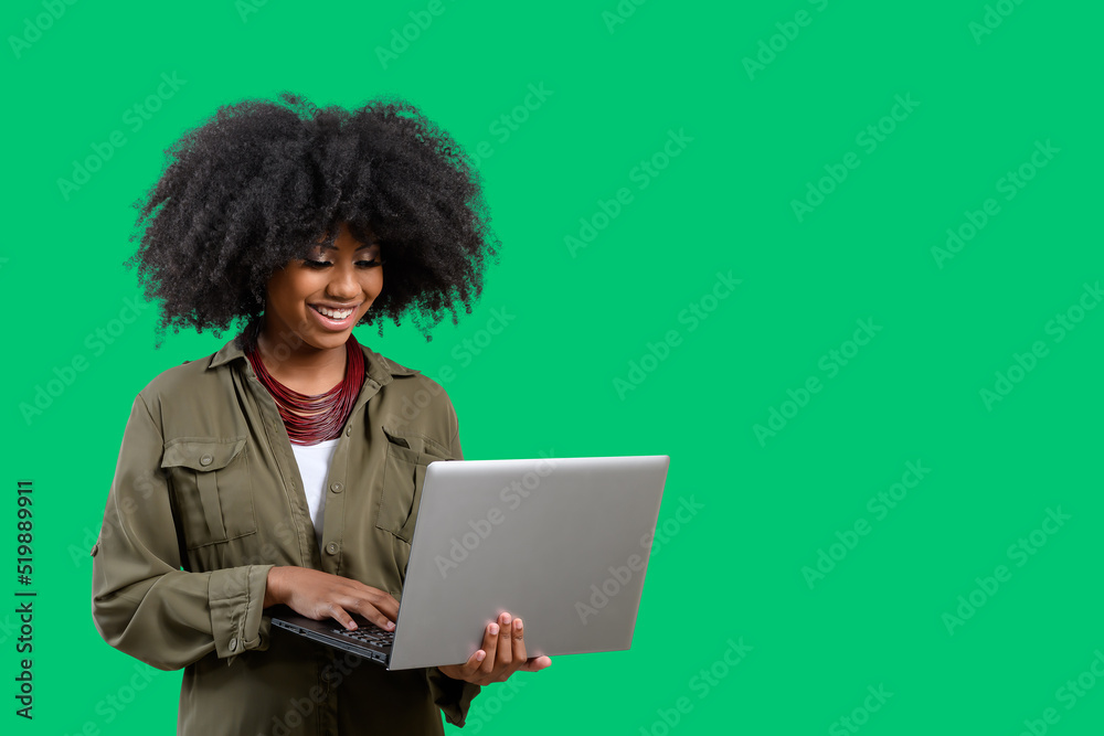 woman holding laptop computer while typing on keyboard, young afro america woman, on green background woman holding laptop computer while typing on keyboard, young afro america woman, on green background