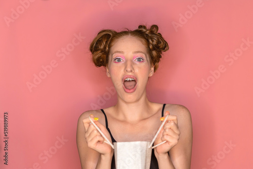 Beautiful cheerful satisfied woman with red hair and big lips rejoice and shout wow from surprise and happiness holding gift in hands on isolated background