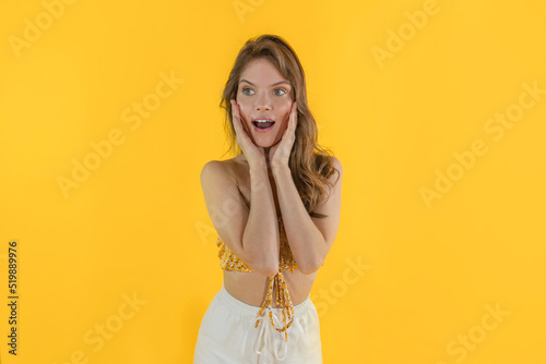 Beautiful girl surprised and shocked feeling happy with long hair and no makeup on isolated background