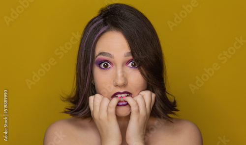 Beautiful sexy woman looking scared at camera holding hands in mouth on isolated background