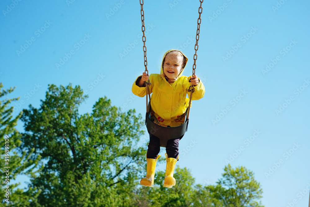 Little blond girl swinging at the park.
