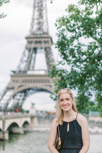 Blonde 30-something woman smiles in front of the Eiffel Tower in Paris © Cavan