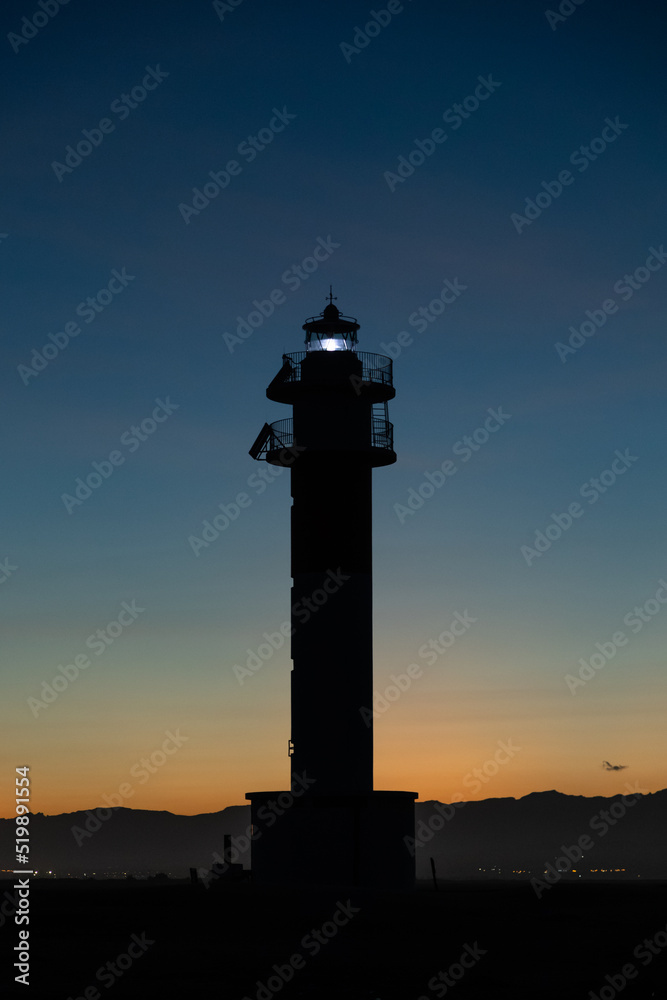 Lighthouse silhouette in Delta de l'ebro Spain during the sunset