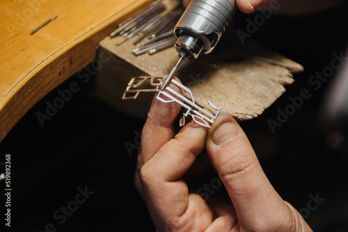 hands of a jeweler working with a file on a blank of silver jewelry photo