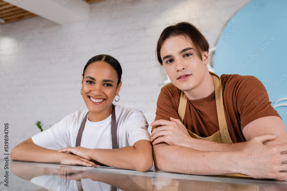 Obraz premium Smiling interracial sellers looking at camera in confectionery.