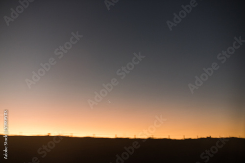 sunset in the mountains with a crescent moon