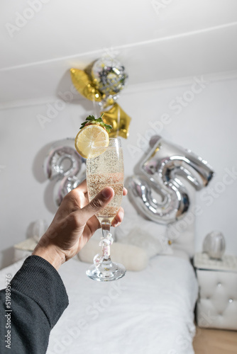 hand holding champagne in a glass with 25 in the background