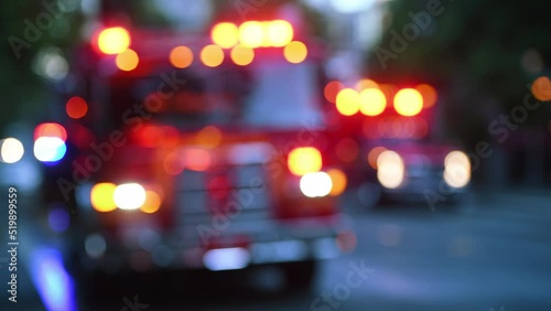Out of focus scene of emergency vehicles with flashing lights working an active fire in early morning light