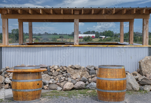 Photography Two oaken wine barrels in front of a pile of stone ruble and a covered stand mad