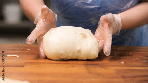 Close up for confectioner at work with the raw dough with raisins. Stock footage. Close up for woman hands in cooking gloves taking a large piece of pastry, making buns from dough.