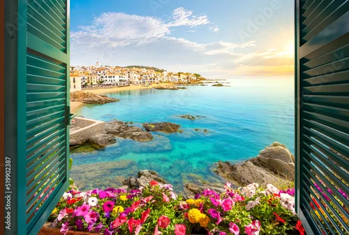 Fototapeta View through an open window with shutters of the whitewashed Costa Brava village of Calella de Palafrugell, Spain, as the sun sets on the Catalonian coast of Southern Spain.