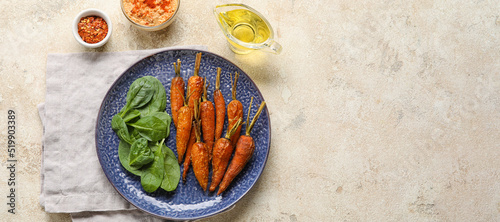 Plate with tasty baked carrots and spinach on grunge background with space for text