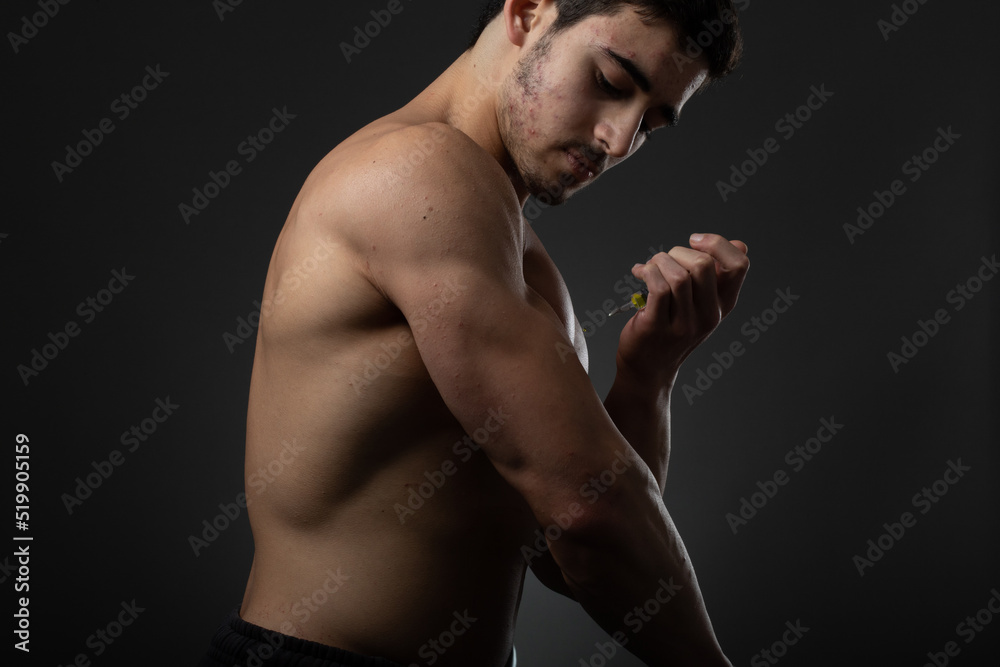 Muscular man with a syringe in his hand. User of anabolic steroids for strength training.