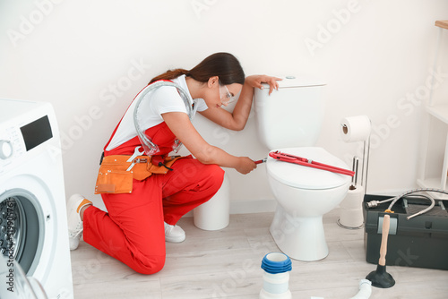 Female plumber fixing toile...