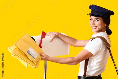 Young postwoman putting let...