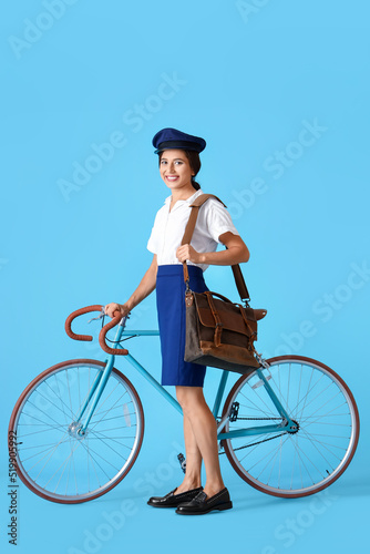 Young postwoman with bicycl...