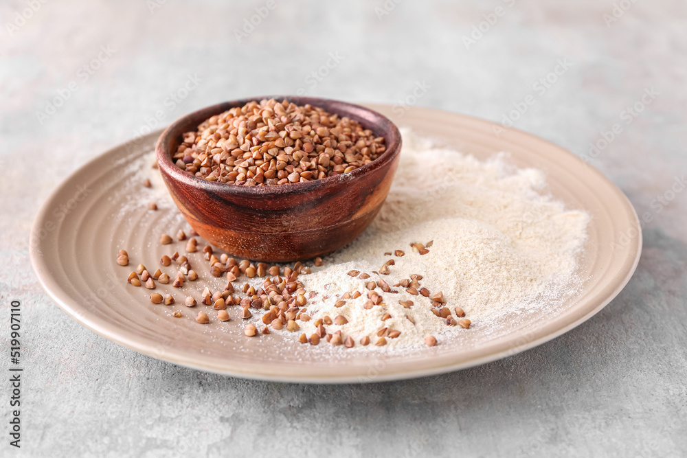 Plate with bowl of buckwheat grains and flour on grunge background Plate with bowl of buckwheat grains and flour on grunge background