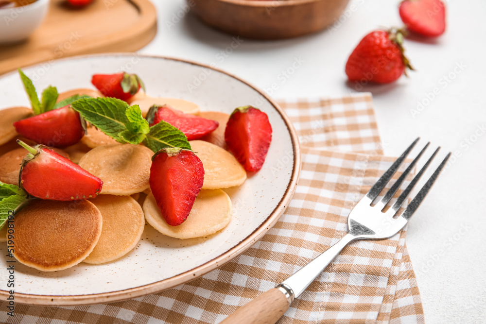 Plate with mini pancakes and delicious strawberry on light table, closeup Plate with mini pancakes and delicious strawberry on light table, closeup