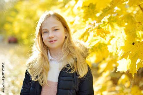 Adorable young girl having fun on beautiful autumn day. Happy child playing in autumn park. Autumn activities for children.