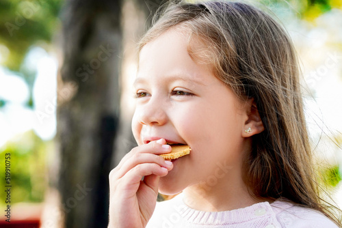 Nila feliz alegre comiendo y disfrutando de una rica y deliciosa galleta en el parque al aire libre