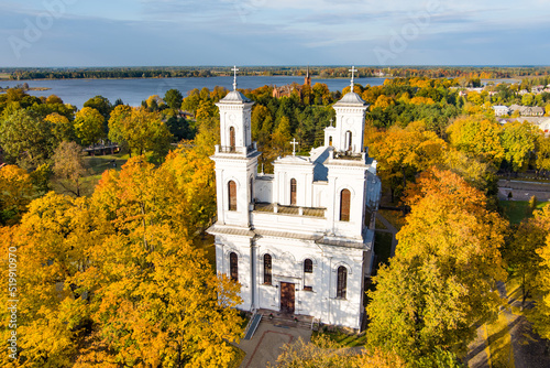 Beautiful aerial view of St. John the Baptist's Church in Birzai surrounded by autumn vegetation on sunny fall day. photo