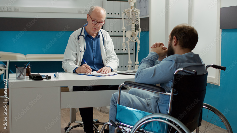 Health specialist doing consultation with wheelchair user in disability friendly cabinet. Medic examining patient with health condition and impairment, using expertise to talk to paralyzed man. Health specialist doing consultation with wheelchair user in disability friendly cabinet. Medic examining patient with health condition and impairment, using expertise to talk to paralyzed man.