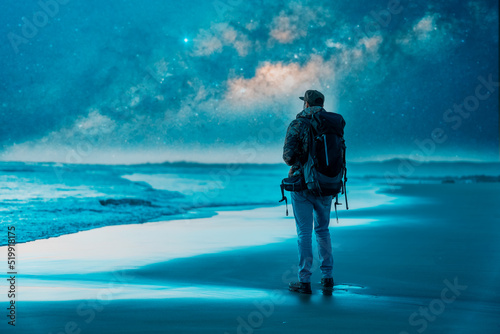 silhouette of a backpacker or traveler looking at the horizon at night with the milky way and the sea in the background