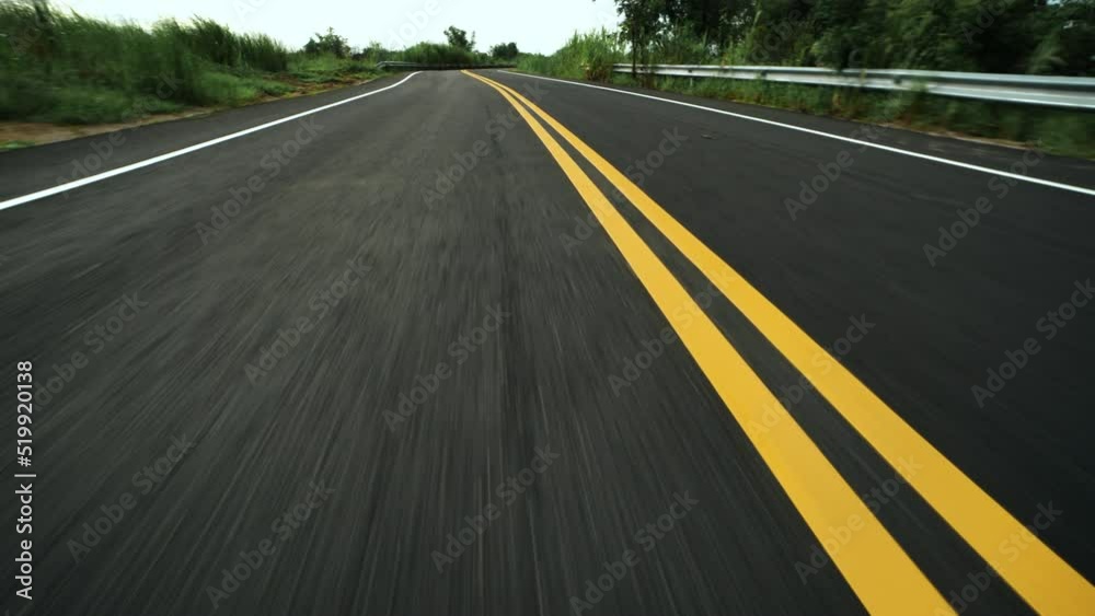 Front pov view of fast car driving on asphalt road with double yellow lines converge
