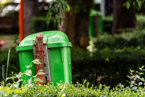 Close rear view of a trash bin over green bush in nature to maintain the environment clean