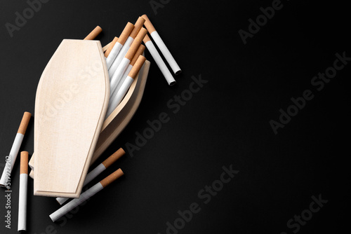 Moody image of real wood coffin filled with cigarettes in darkness with copy space concept for quit smoking to prevent death, lung cancer awareness and cigarettes kill