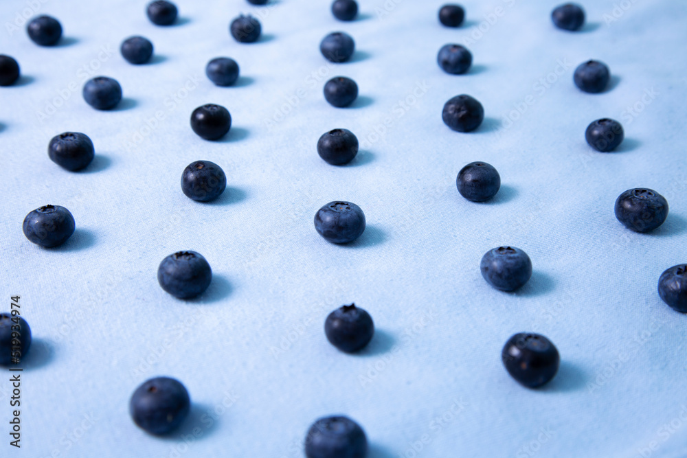 Blueberries lie in a row on a blue background