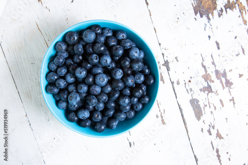 Blueberries in a round blue bowl on a wooden table