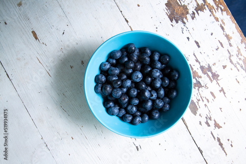 Top view of round bowl with blueberries on wooden table