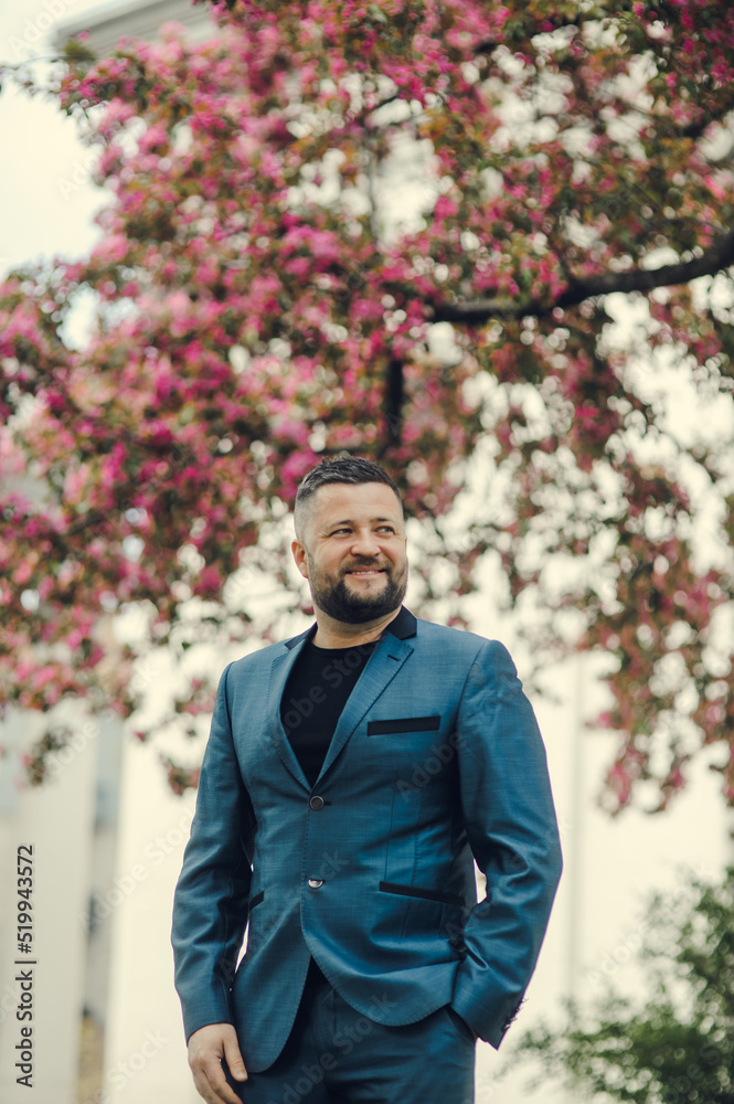 Portrait of a successful young guy.Portrait of handsome successful smiling man near flowering tree in park. Portrait of a successful young guy.Portrait of handsome successful smiling man near flowering tree in park.