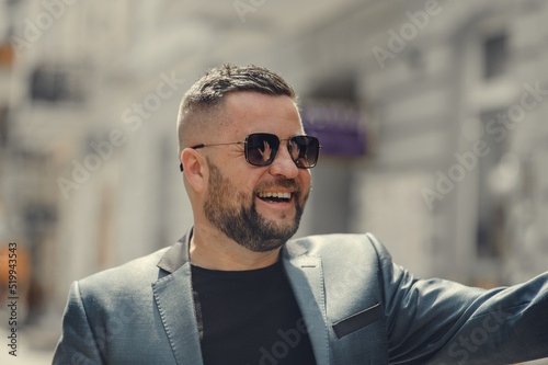 Happy smiling man on city street.Portrait of handsome confident stylish hipster